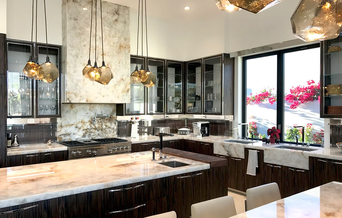 A kitchen with marble counter tops and white cabinets.