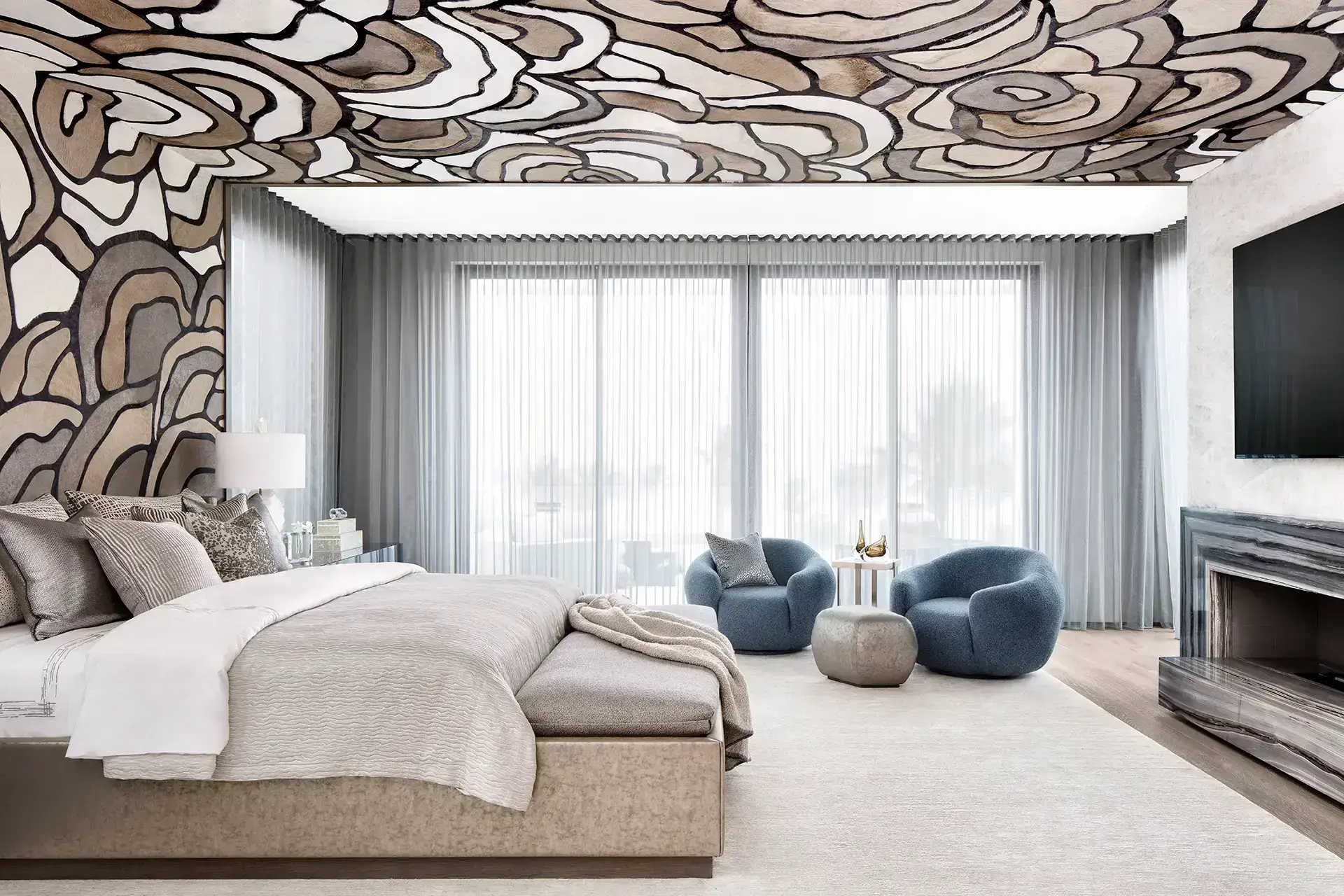 Modern bedroom with neutral tones and large windows.